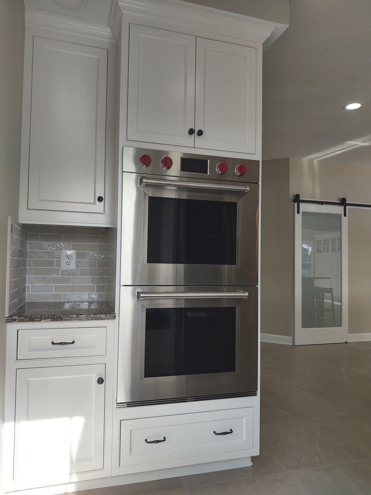A kitchen with white cabinets and a stainless steel oven