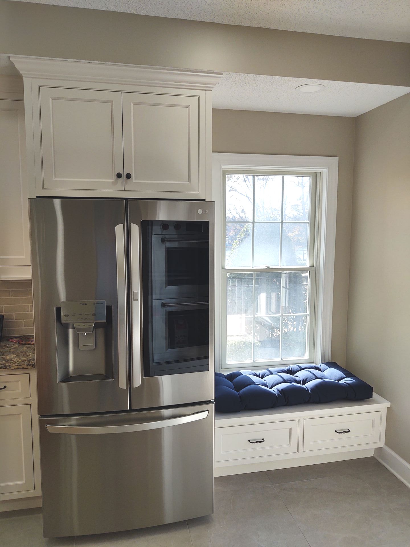 A kitchen with a stainless steel refrigerator and a window seat