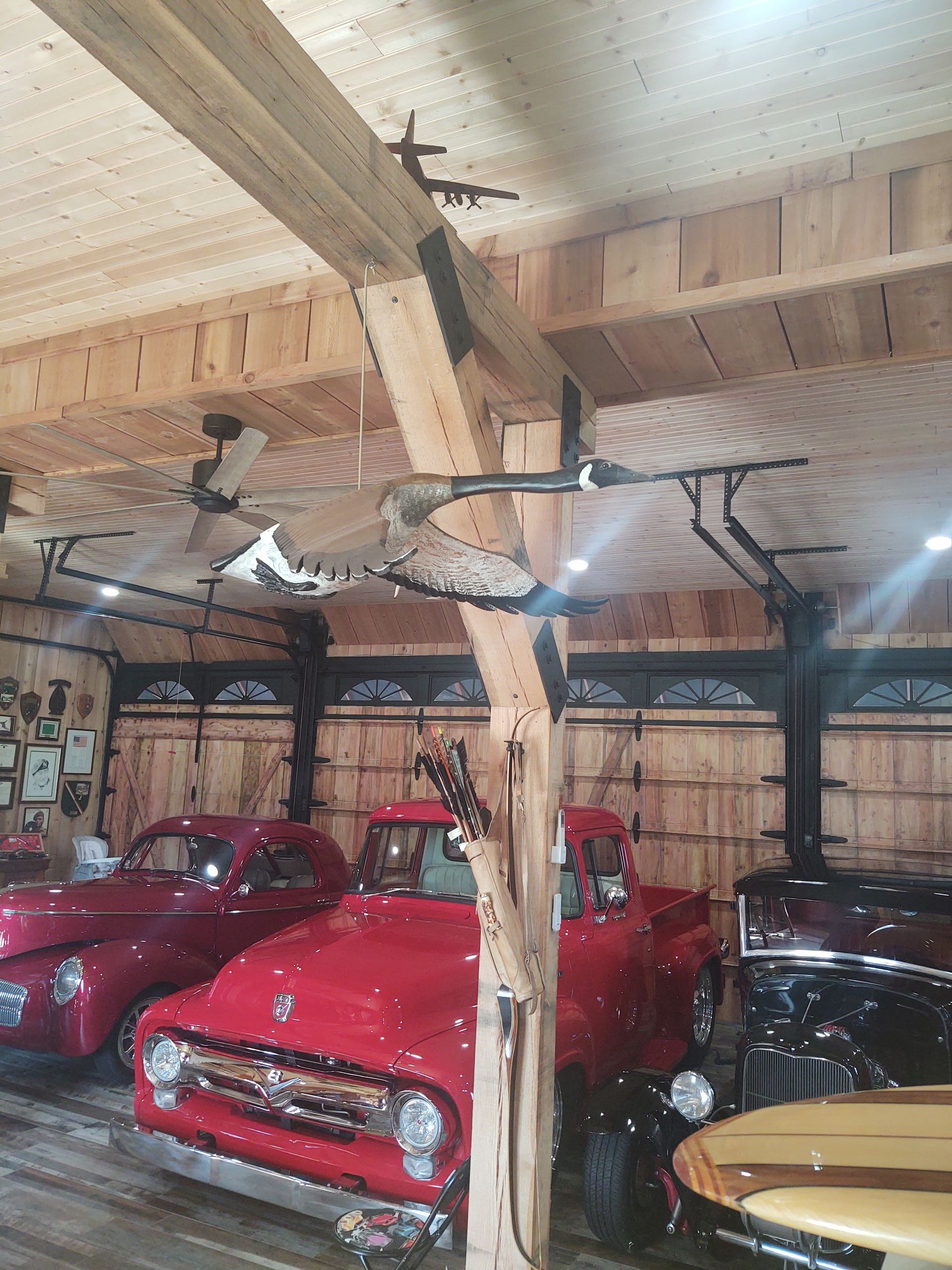 A row of red trucks are parked in a wooden garage.