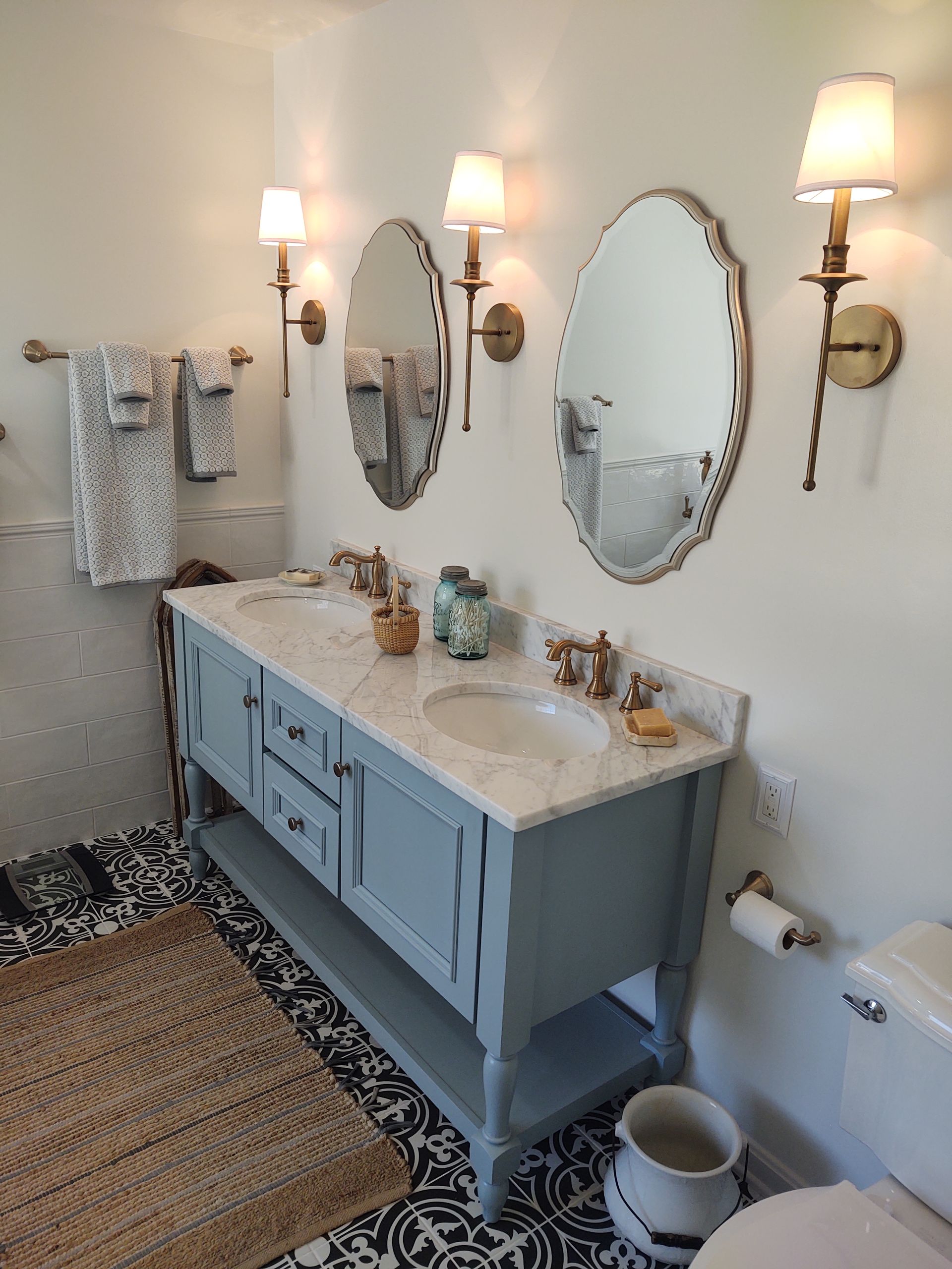A bathroom with two sinks , two mirrors and a toilet.