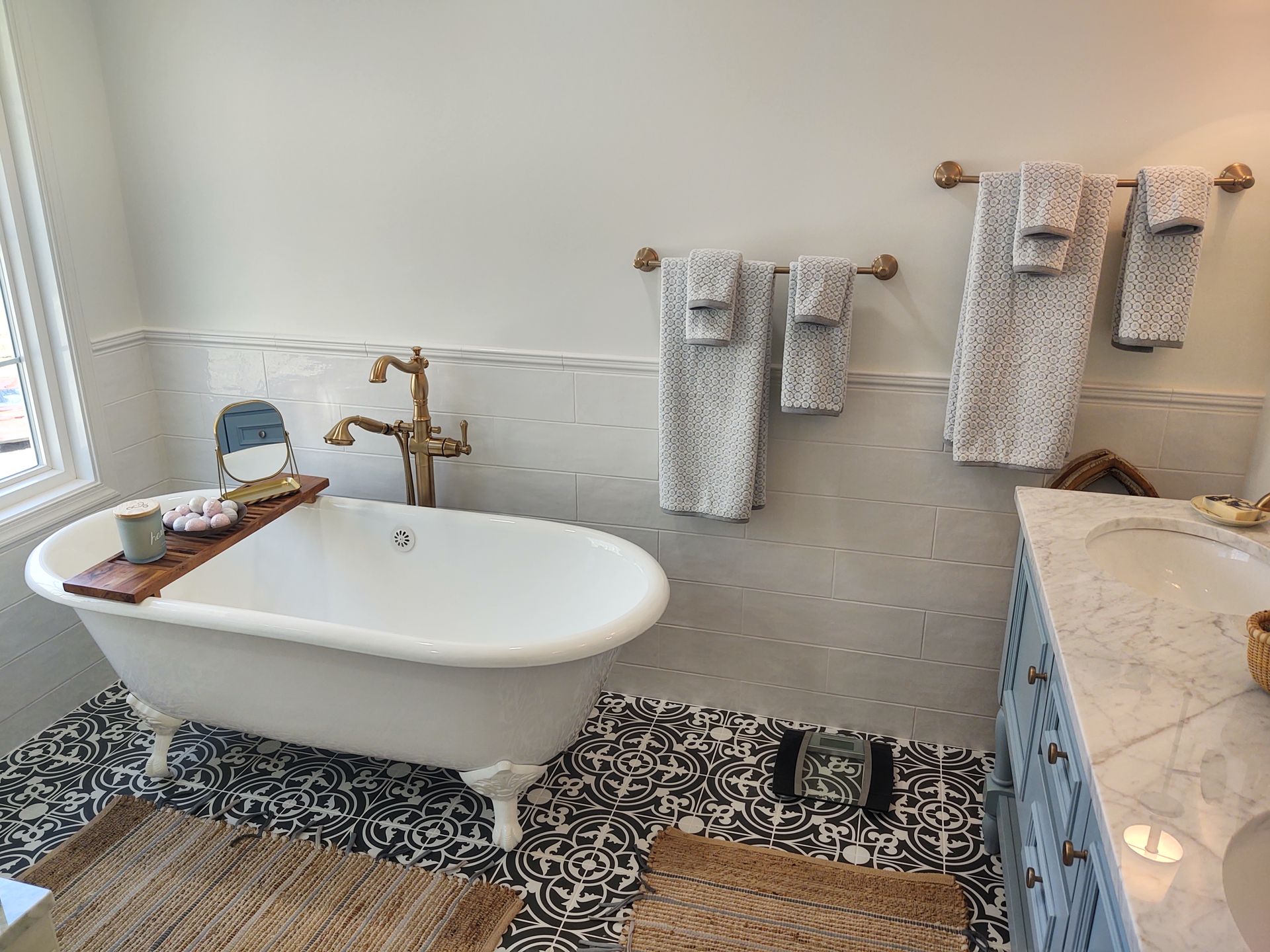 A bathroom with a bathtub , sink , and towels hanging on the wall.