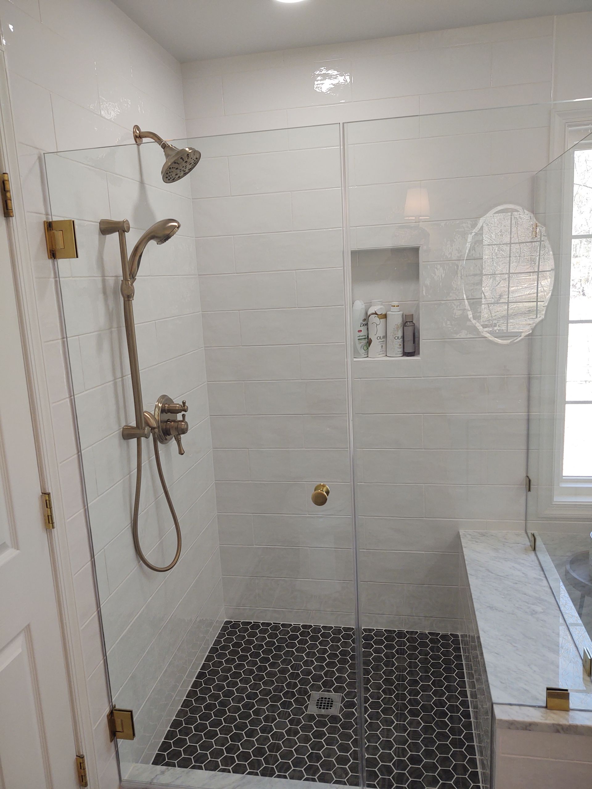 A bathroom with a walk in shower with a glass door.