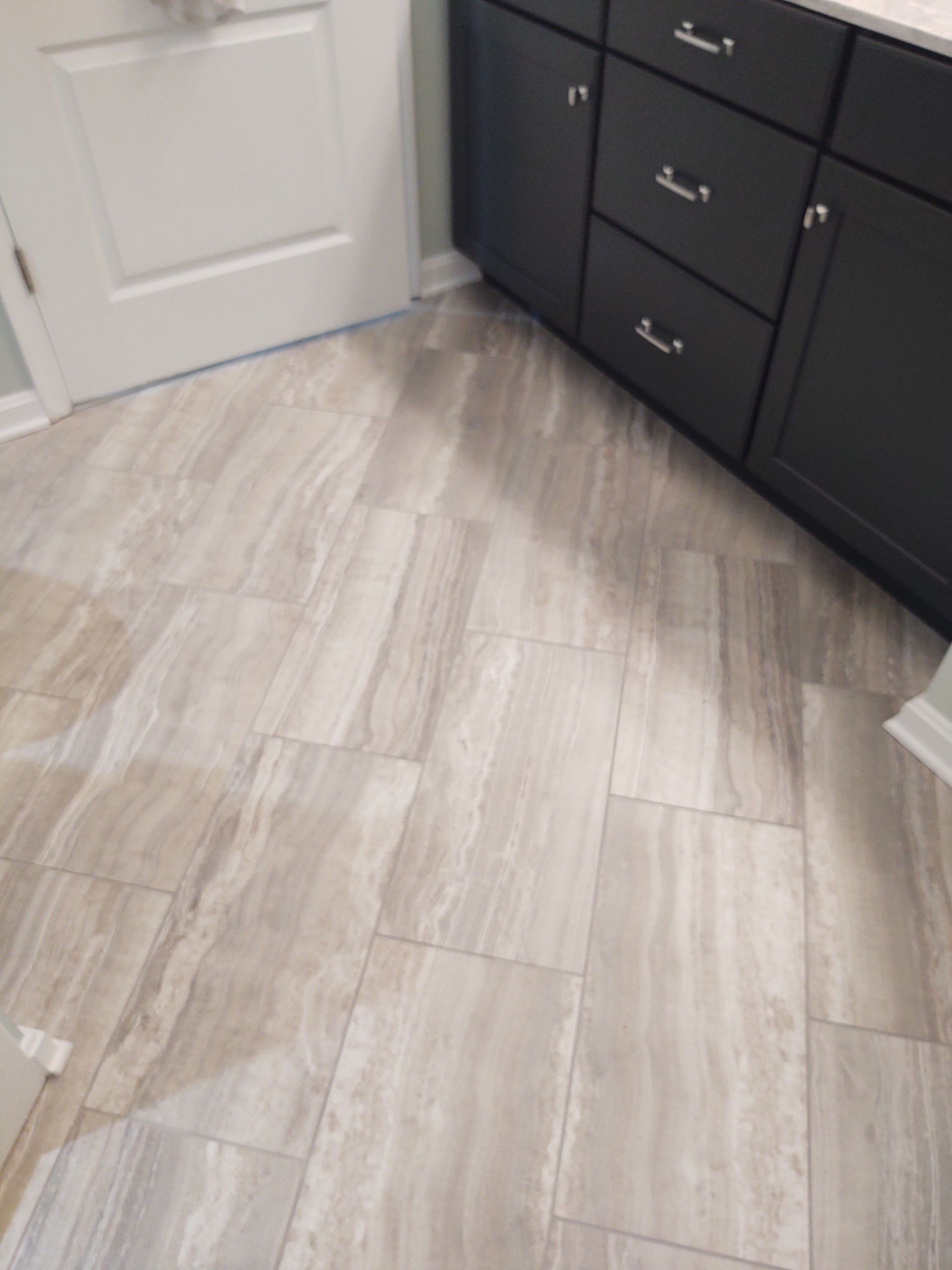 A bathroom with a tiled floor and black cabinets.