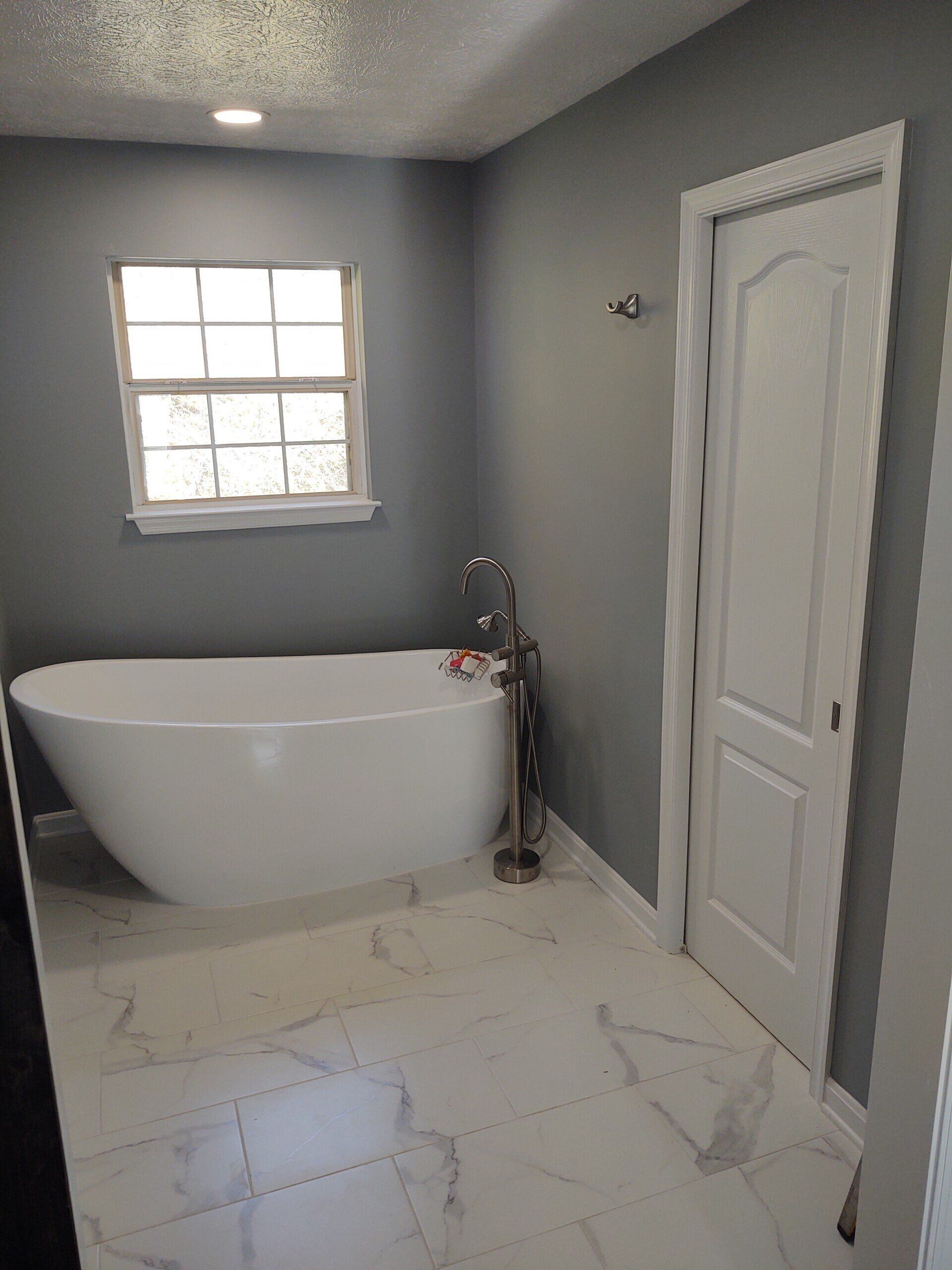 A bathroom with a bathtub and a window.