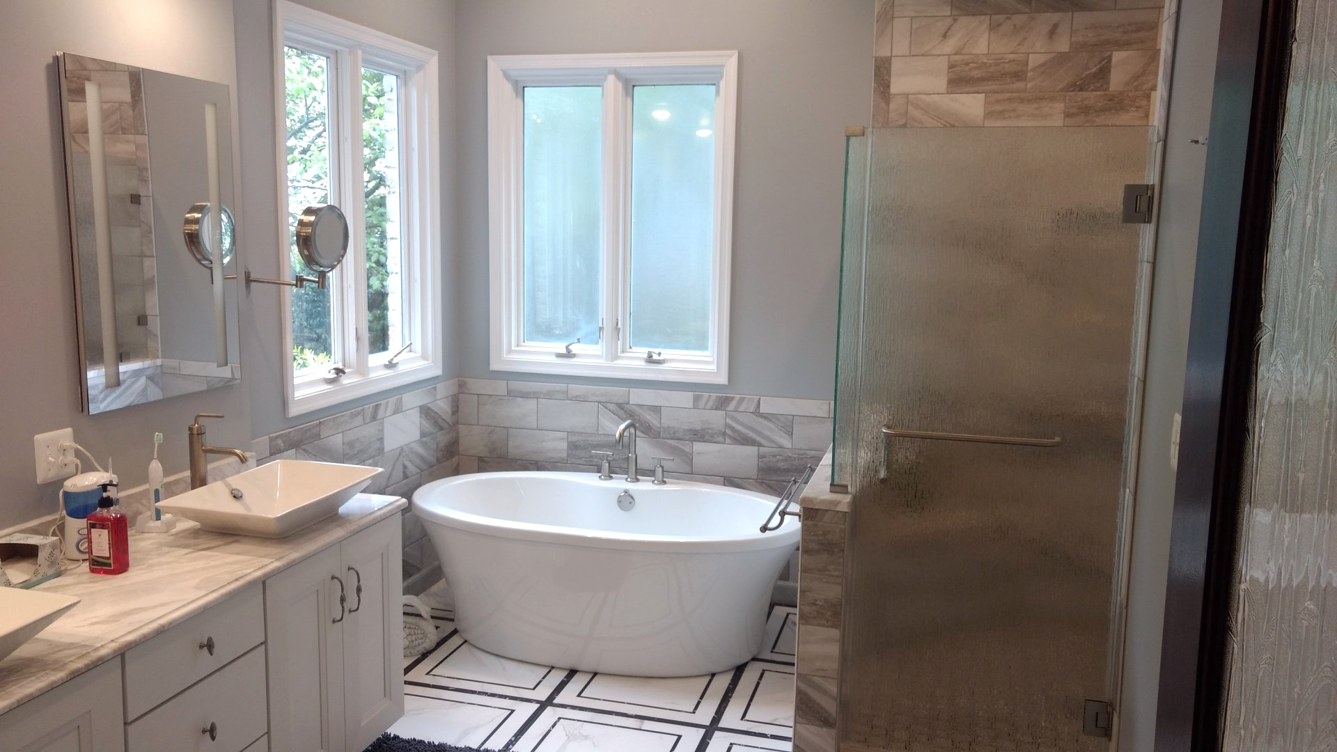 A bathroom with a tub , sink , mirror and shower.