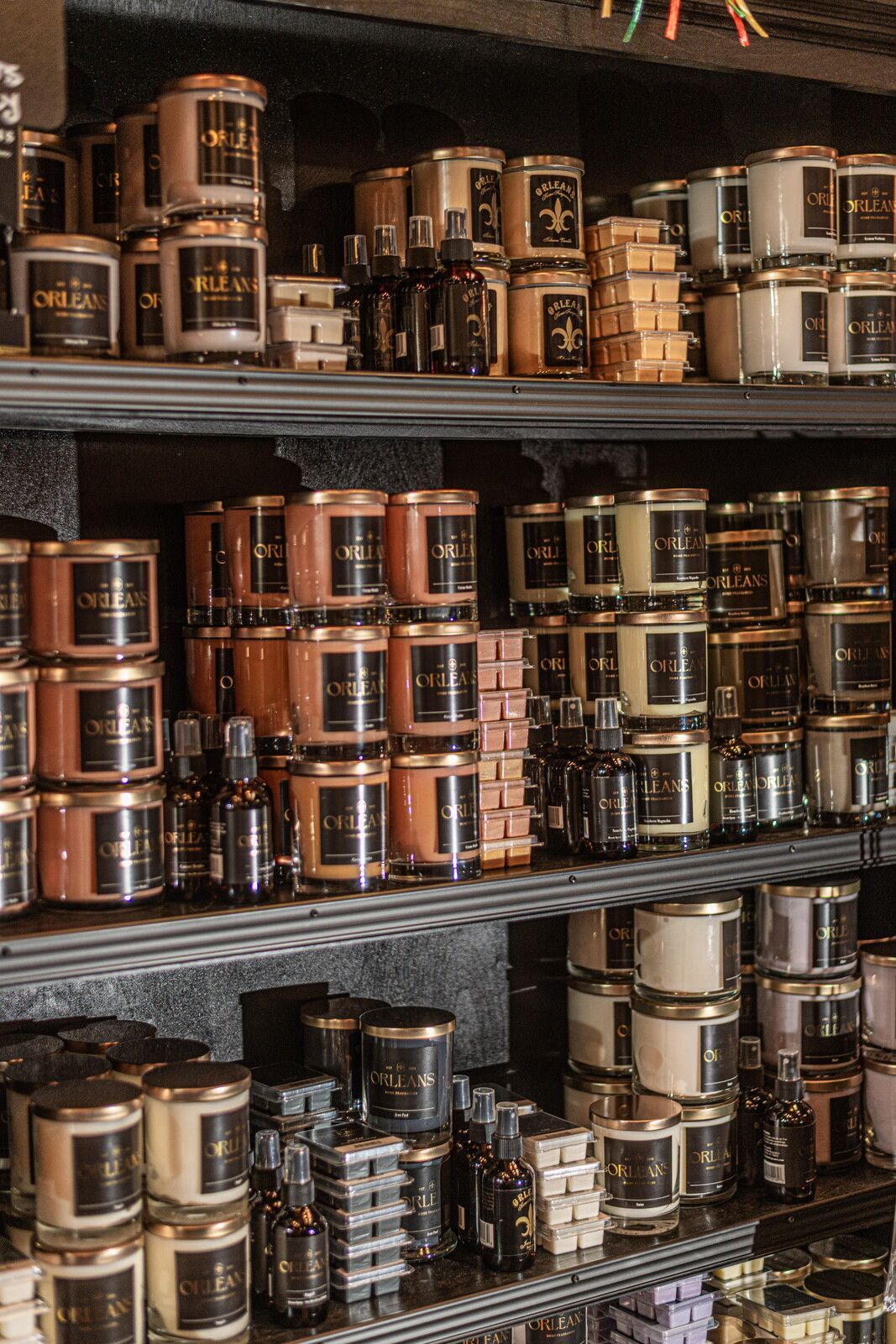 Shelves stocked with various candles in jars and small bottles.