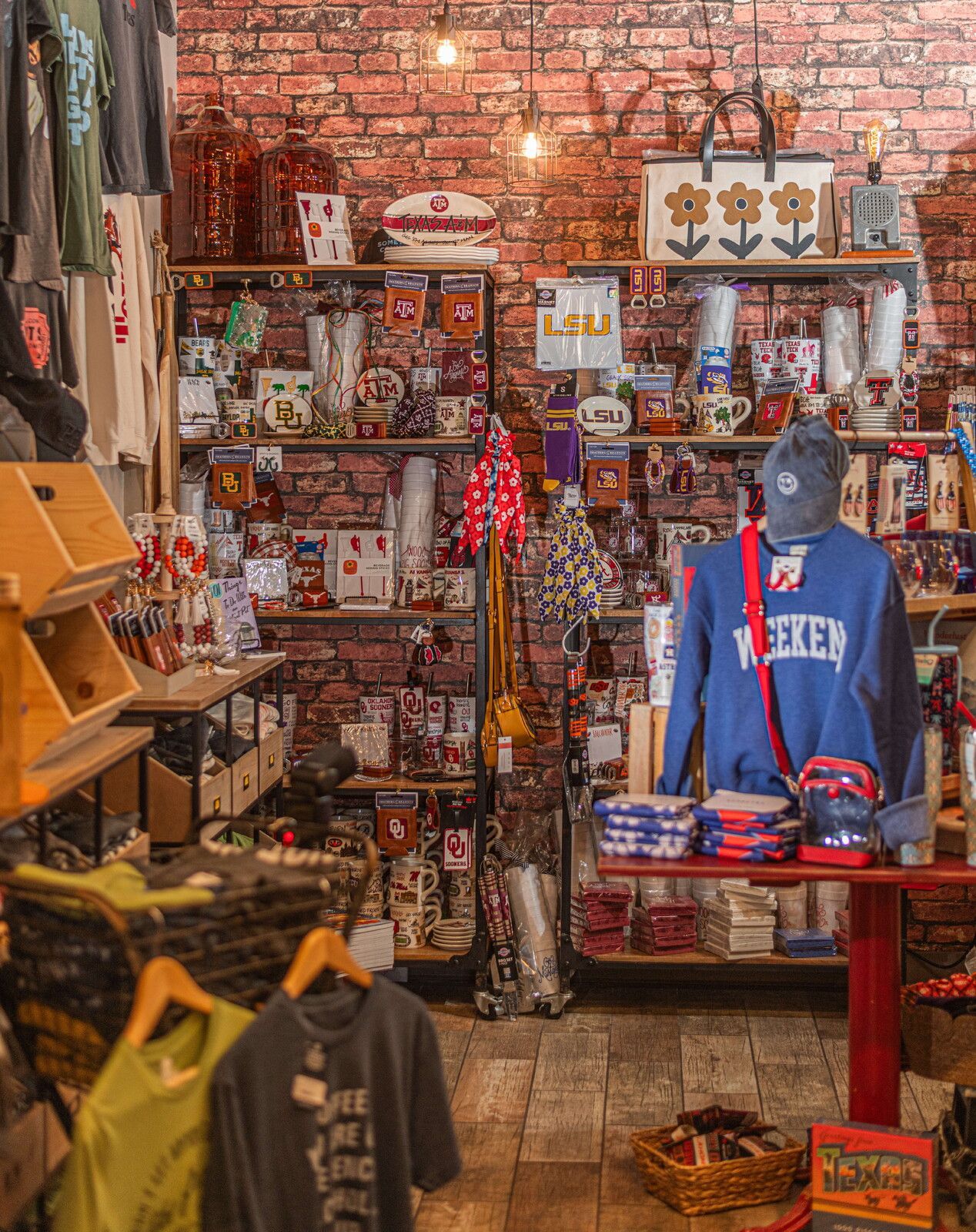 Inside a gift shop with brick walls, shelves stocked with mugs, clothing, and accessories.