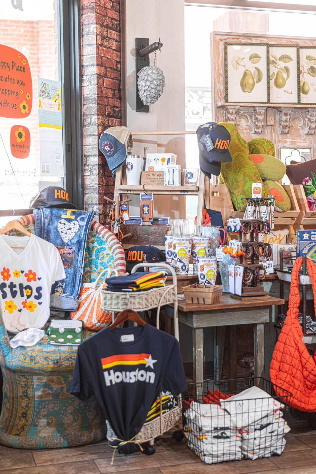 Inside a gift shop, merchandise is on display; clothing, mugs, and decor. The setting is well-lit, with brick and wood elements.