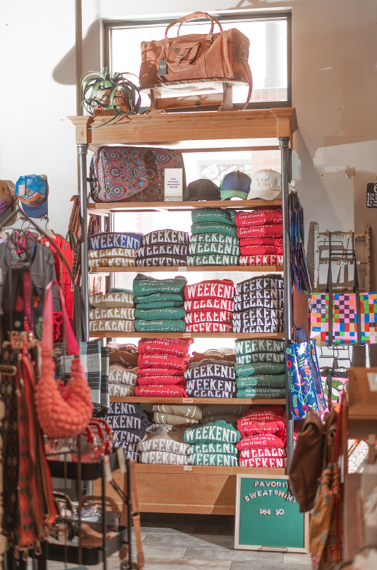 Retail display of apparel and bags; shelves of folded shirts with 