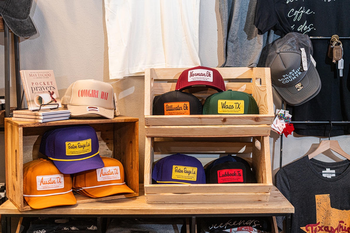 Display of hats in wooden crates, featuring various colors and logo patches. Store setting.