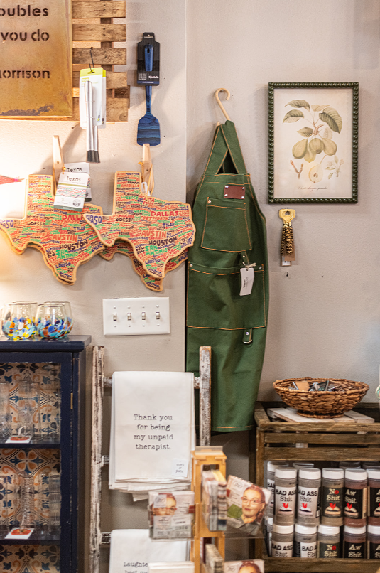 Corner display with apron, Texas map art, spices, and decorative items.