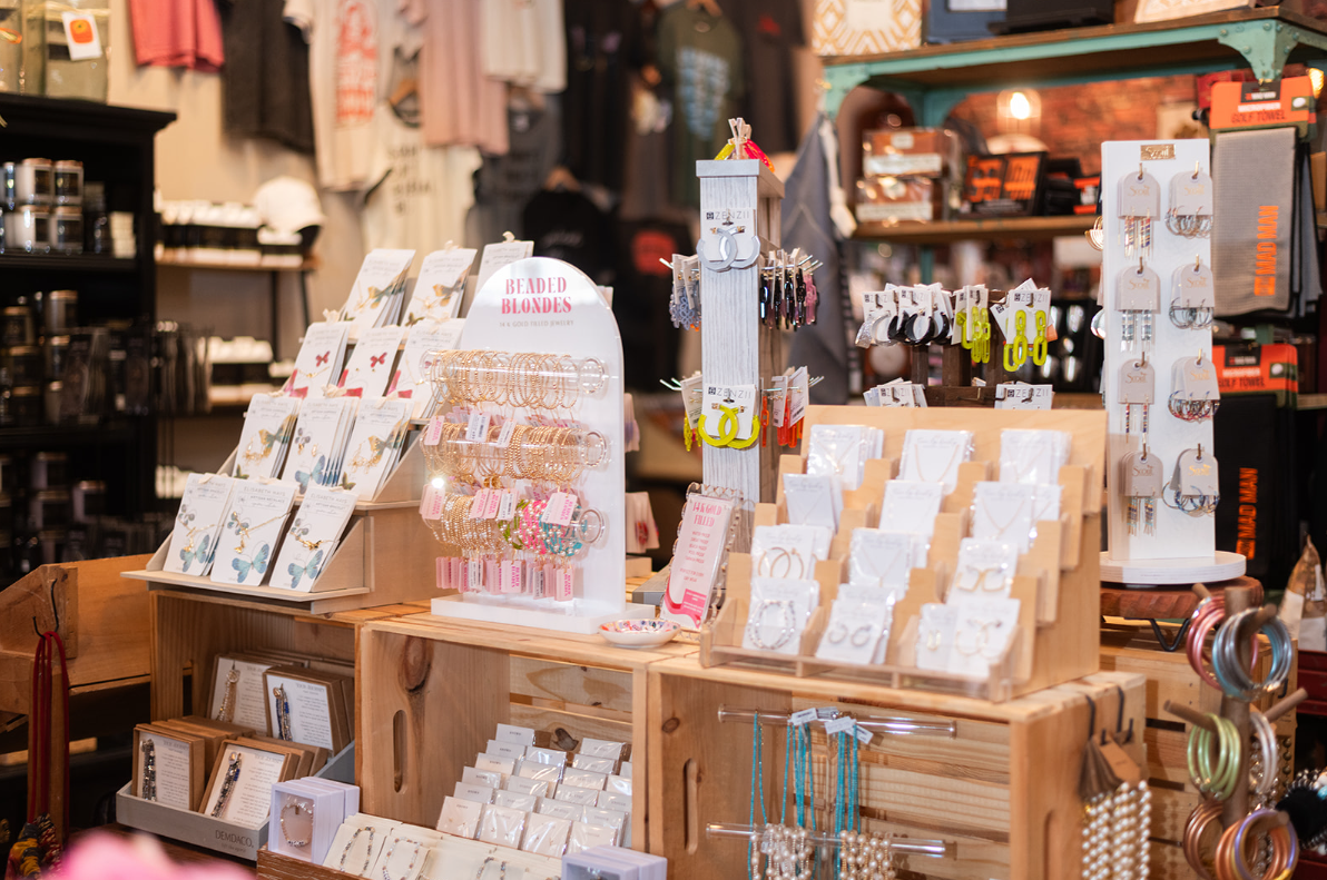 Jewelry display in a store, wooden crates and shelves, various necklaces, earrings, and cards.