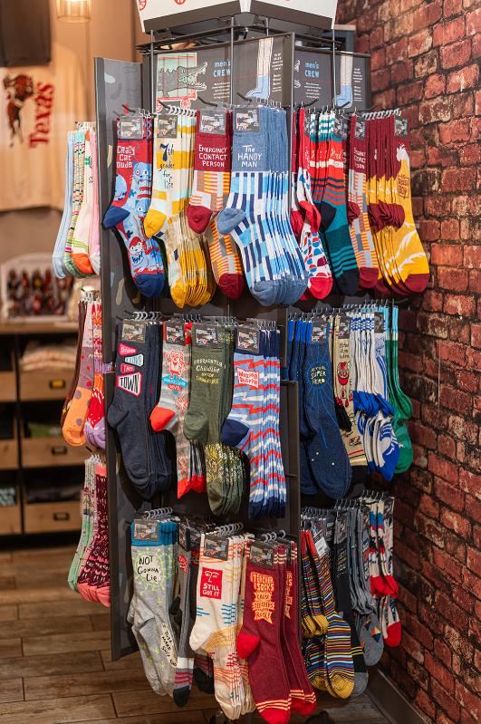 Sock display rack filled with colorful patterned socks, set against a brick wall.