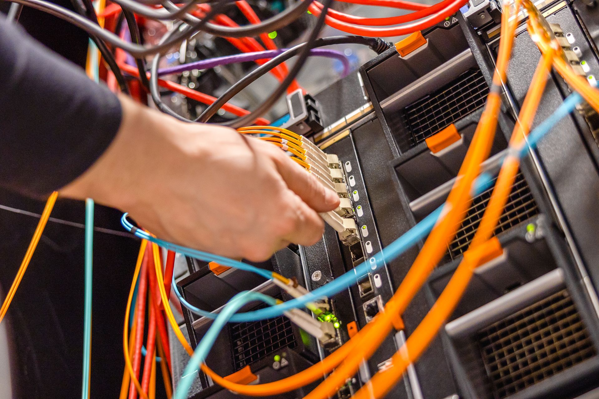 A person is working on a server with a bunch of wires coming out of it.