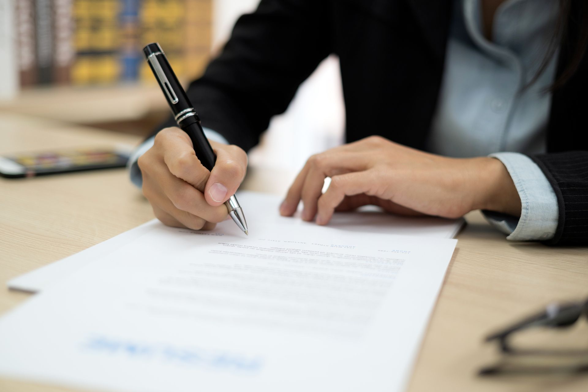 A woman is writing on a piece of paper with a pen.