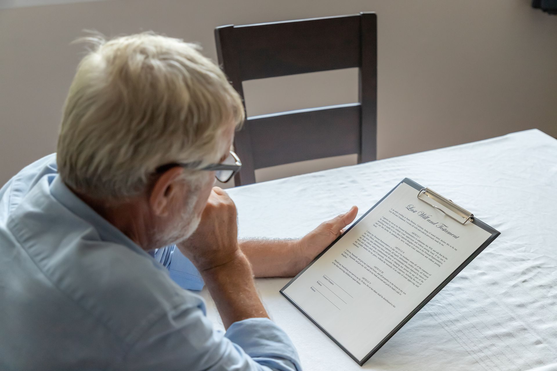A close-up of a senior man examining and checking his last will and testament at a table.