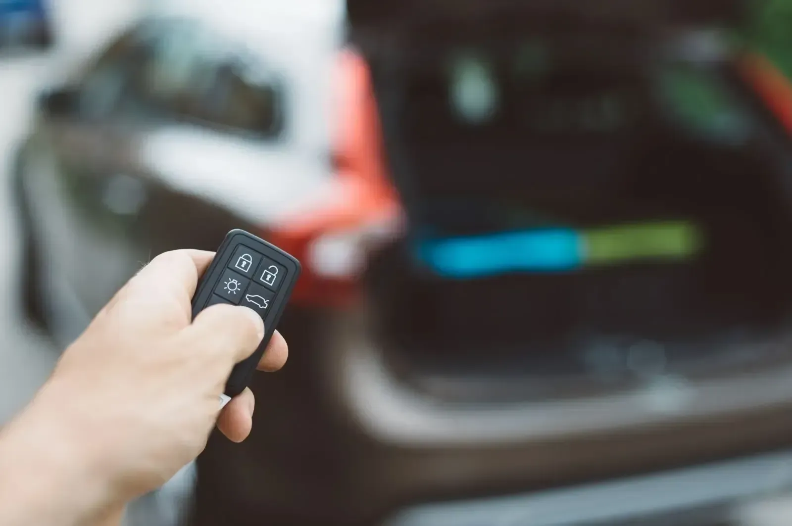 Man holding key fob to open trunk of car
