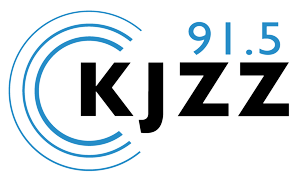 Logo for radio station KJZZ 91.5, featuring station letters and frequency, with blue radio wave design.