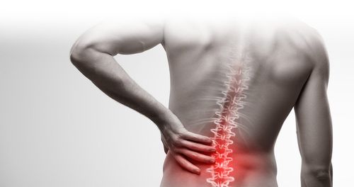 Man with visible spine, hand on lower back, red highlight indicating pain.