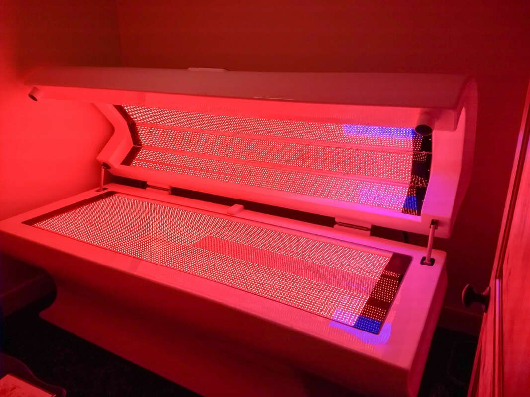 Red light therapy bed. Open, emitting red light.