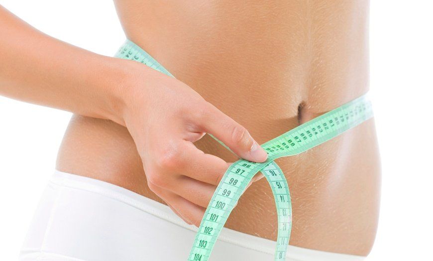 Person measuring waist with a green measuring tape.