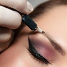 Person receiving microblading treatment on their eyebrow.