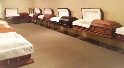 Funeral showroom with several open caskets lined up on display