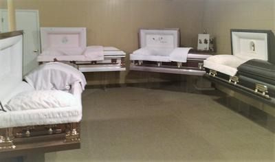 Funeral home showroom with several open caskets arranged around a room
