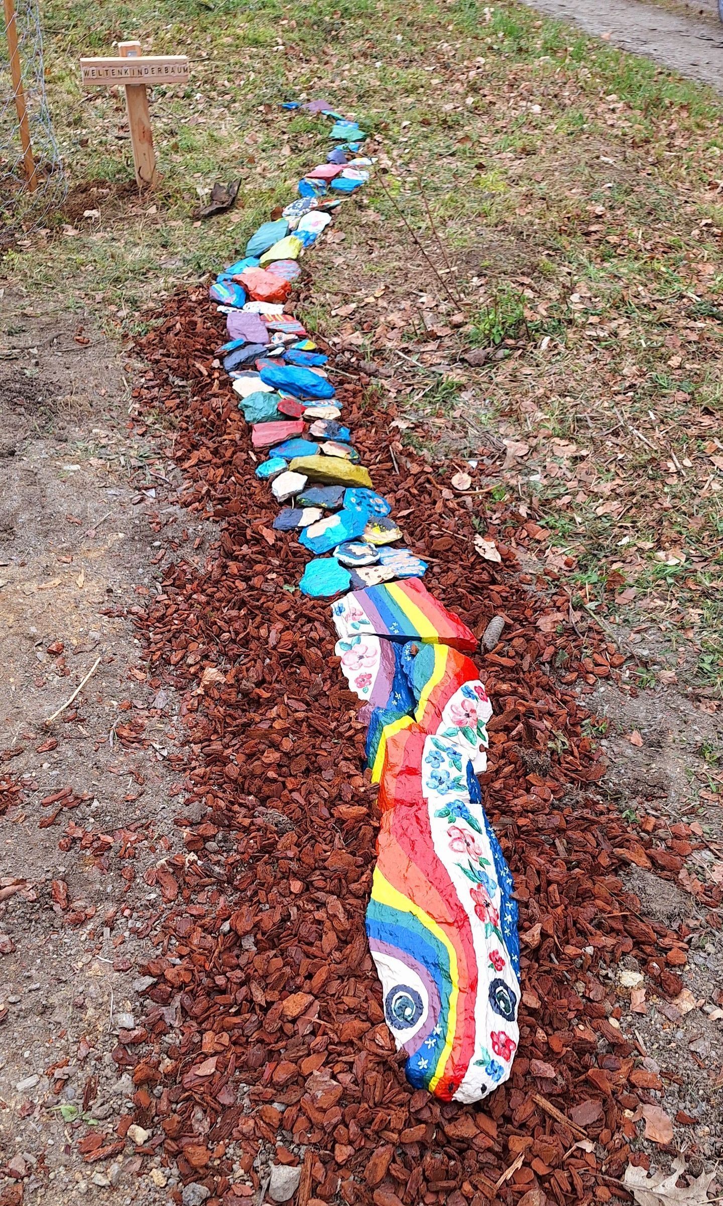 Eine bunte Schlange aus Steinen liegt auf dem Boden.