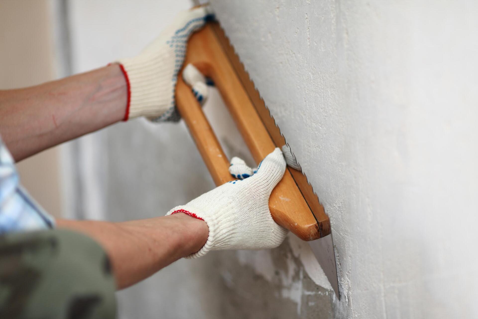worker scraping the paint in the wall