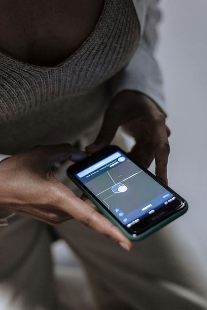 Person holding a smartphone, displaying a blue-toned app interface with a white circle and crosshairs.