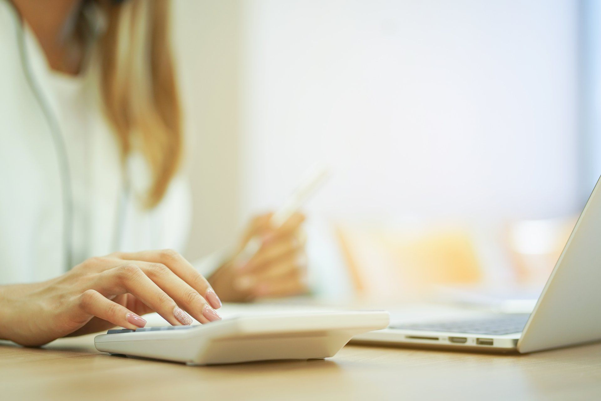 Une femme utilise une calculatrice et détient une carte de crédit.