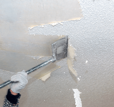 A worker scraping off the popcorn ceiling