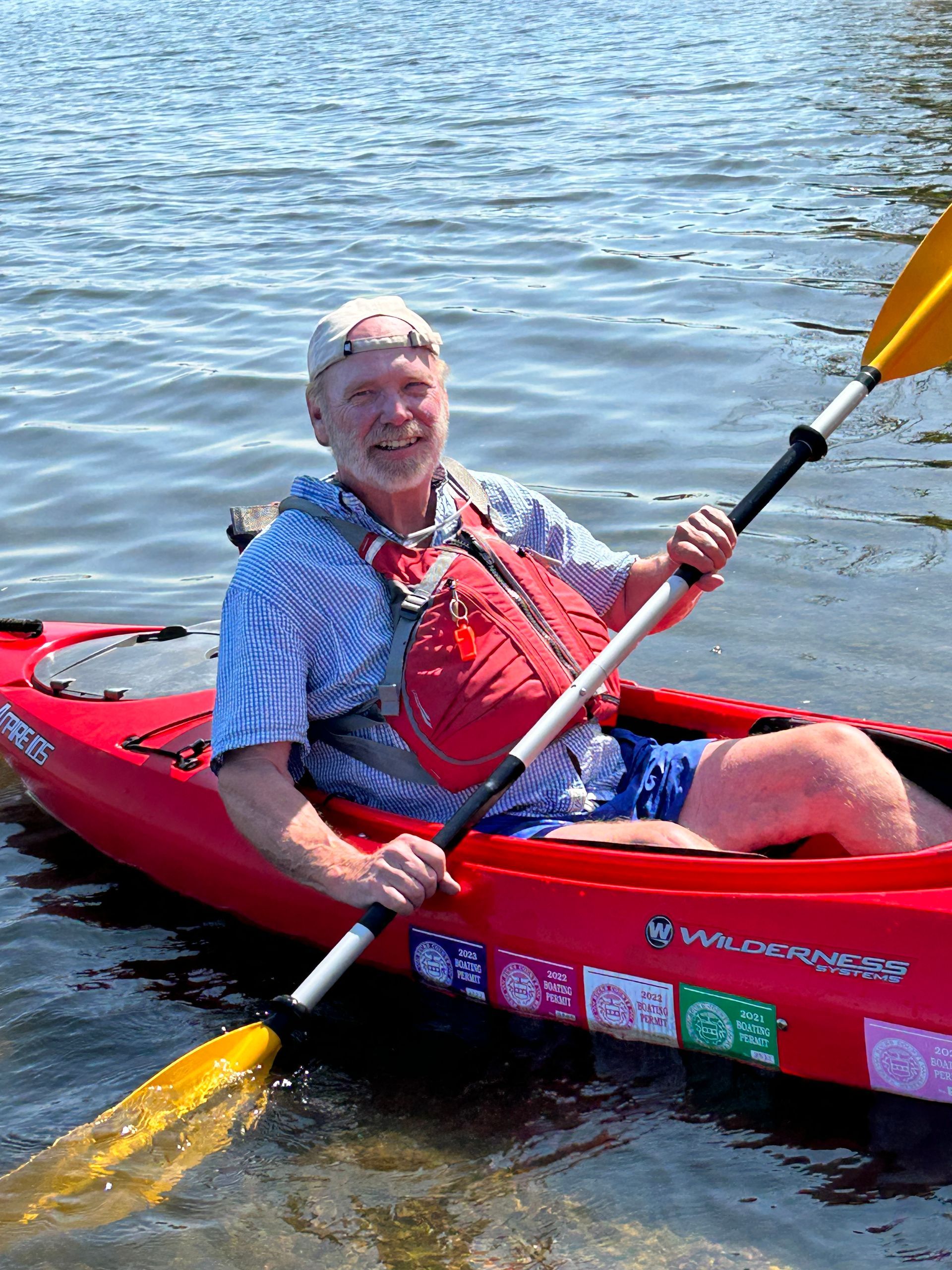 A man is sitting in a red kayak with a yellow paddle.