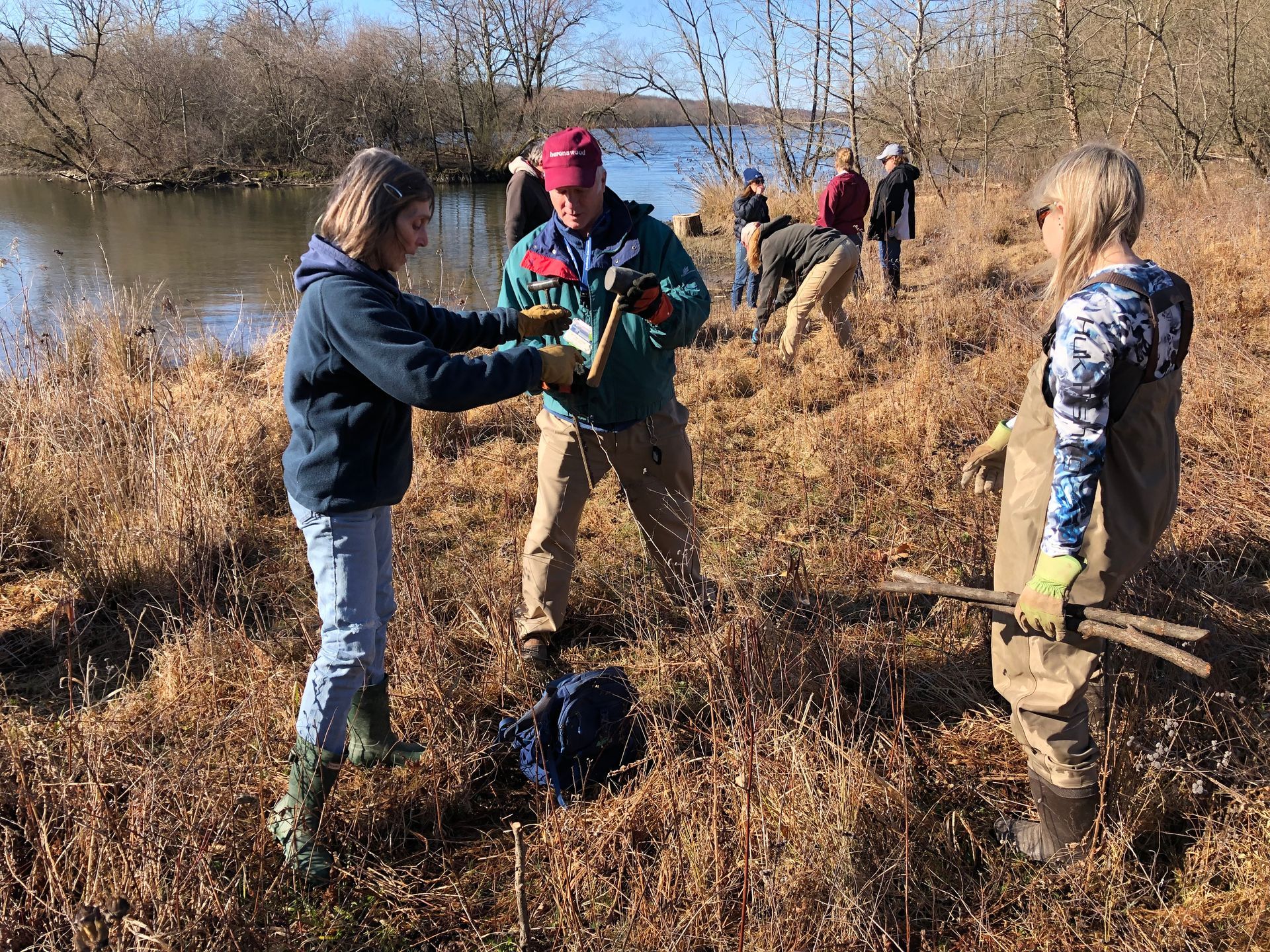A group of people are standing in a field near a body of water.