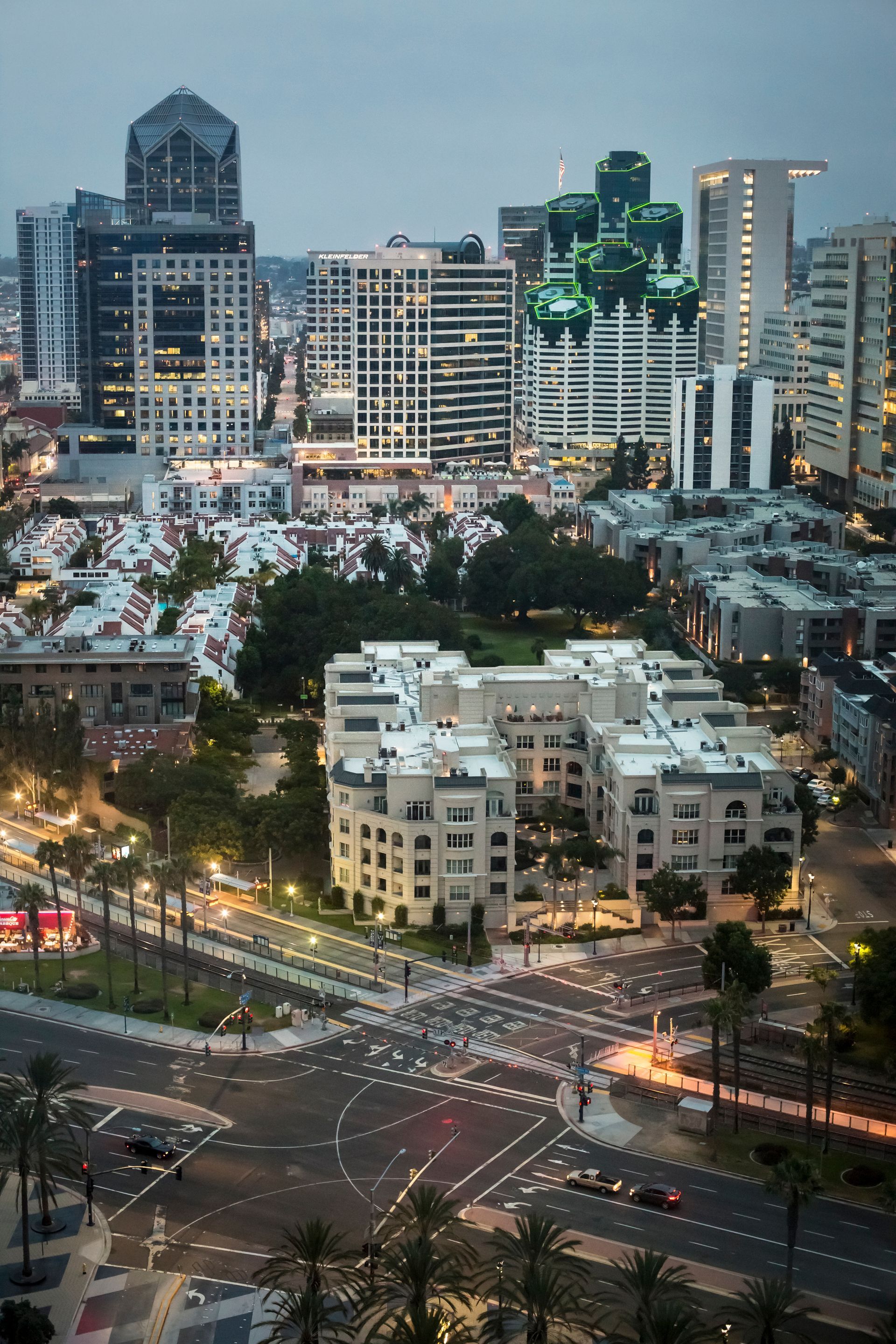 City skyline at dusk above a busy intersection, with lit buildings and traffic lights.