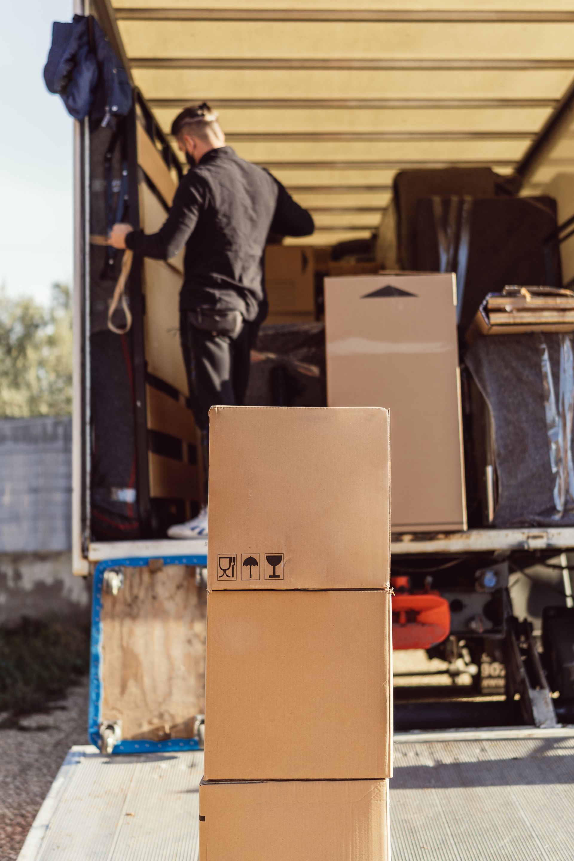 Person loading cardboard boxes into a moving truck from a ramp