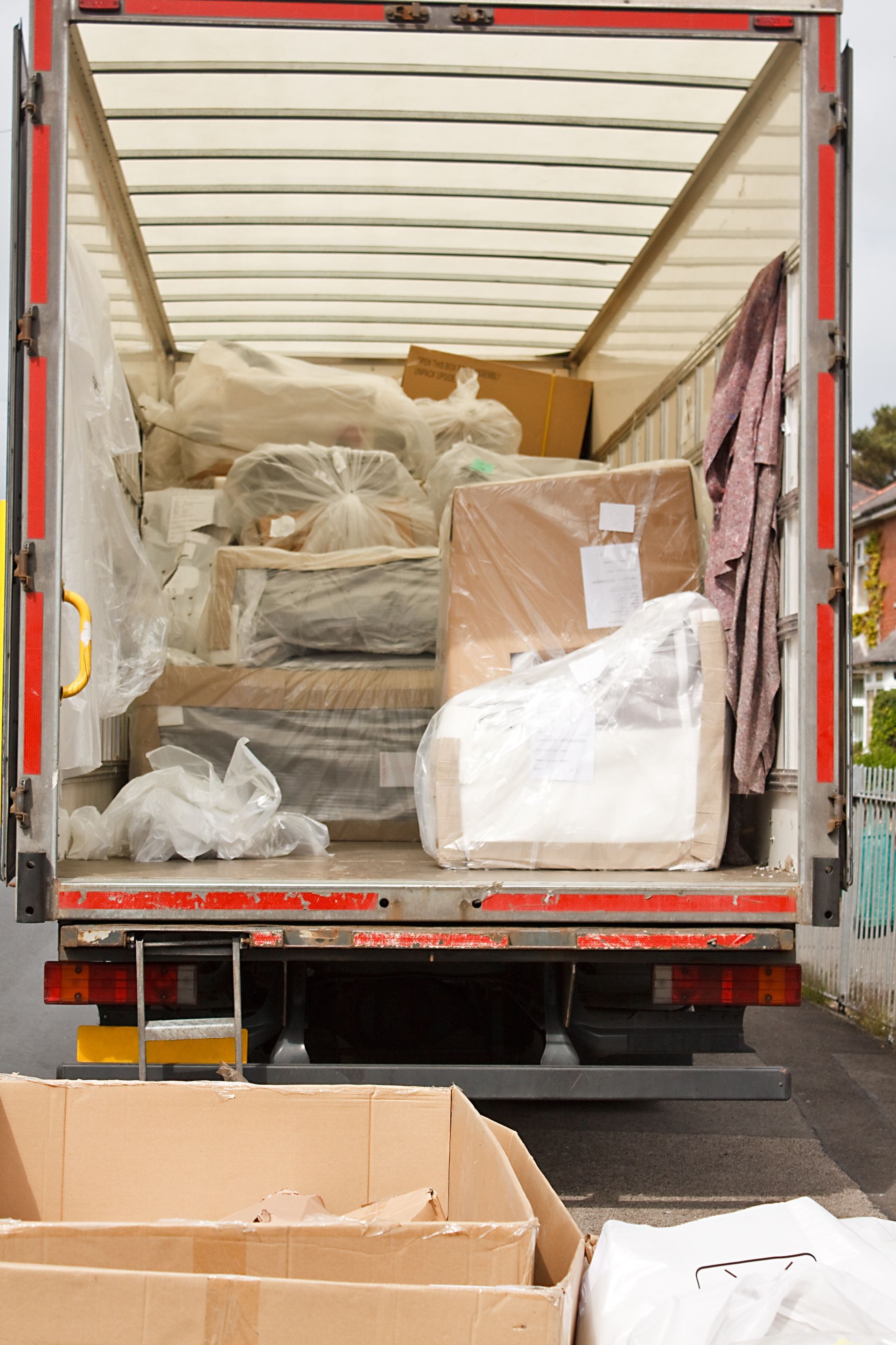 Open truck full of packed boxes and wrapped furniture, parked on a street. Open truck full of packed boxes and wrapped furniture, parked on a street.