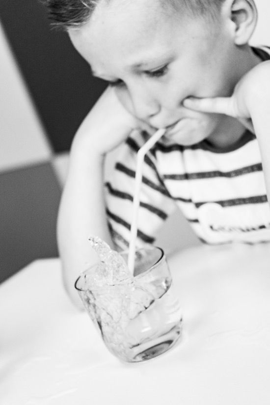 Een jonge jongen drinkt door een rietje uit een glas.