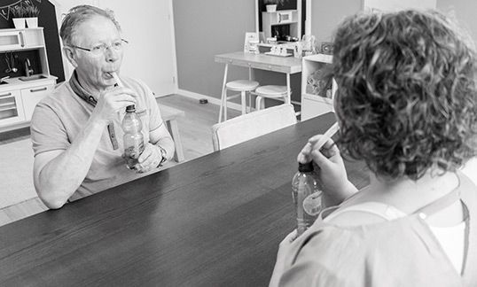 Een man en een vrouw zitten aan een tafel en drinken uit flessen.