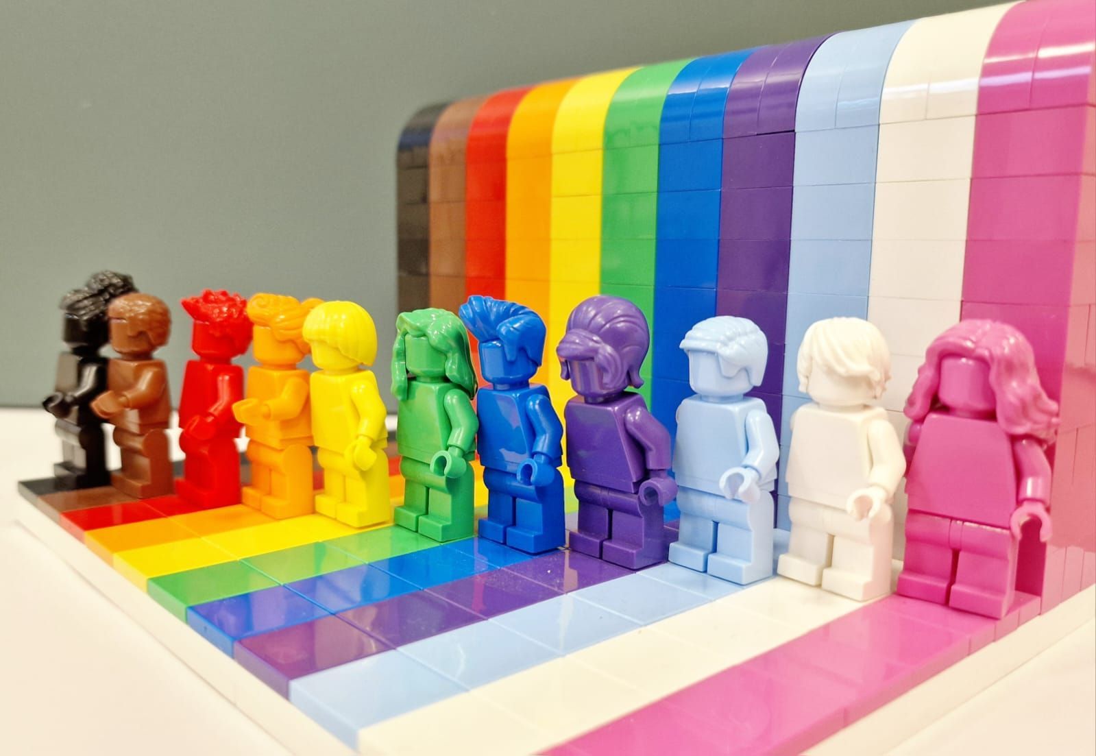 Een groep lego-figuren die naast elkaar staan op een regenboogachtergrond