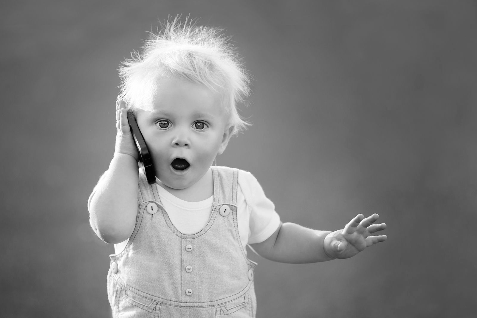 Een baby praat op een mobiele telefoon op een zwart-witfoto.