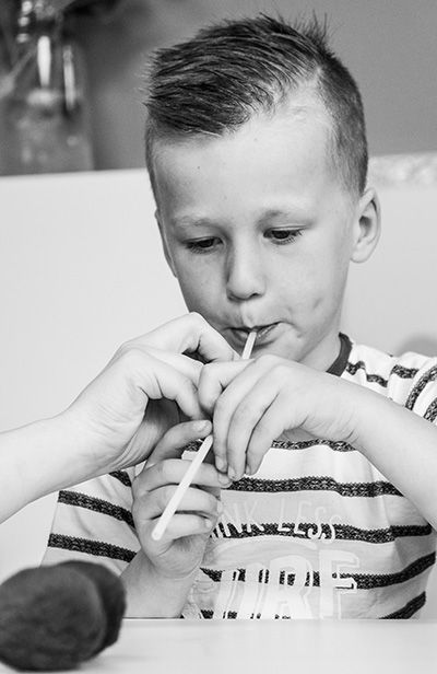 Een jonge jongen drinkt door een rietje terwijl hij aan een tafel zit.
