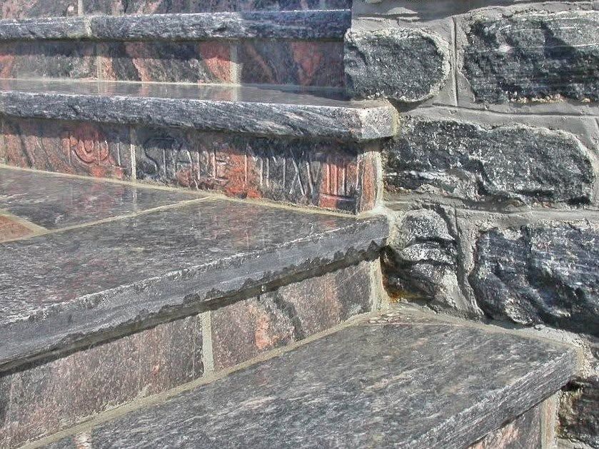 Stone steps with rough gray and reddish masonry in close-up.