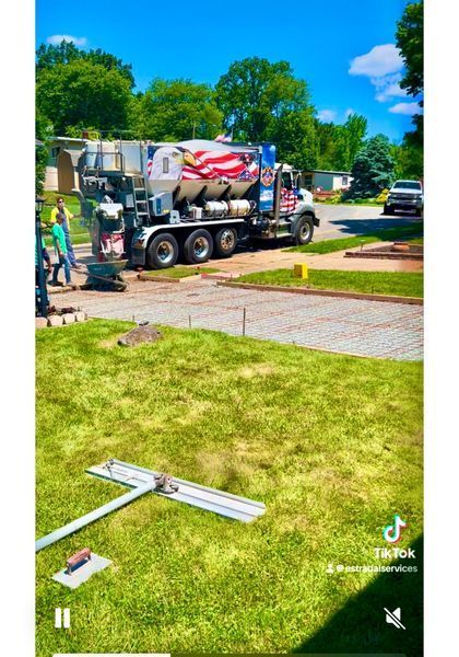 Cement truck pours concrete on a sunny day. Workers and tools are in the foreground, with an American flag design.
