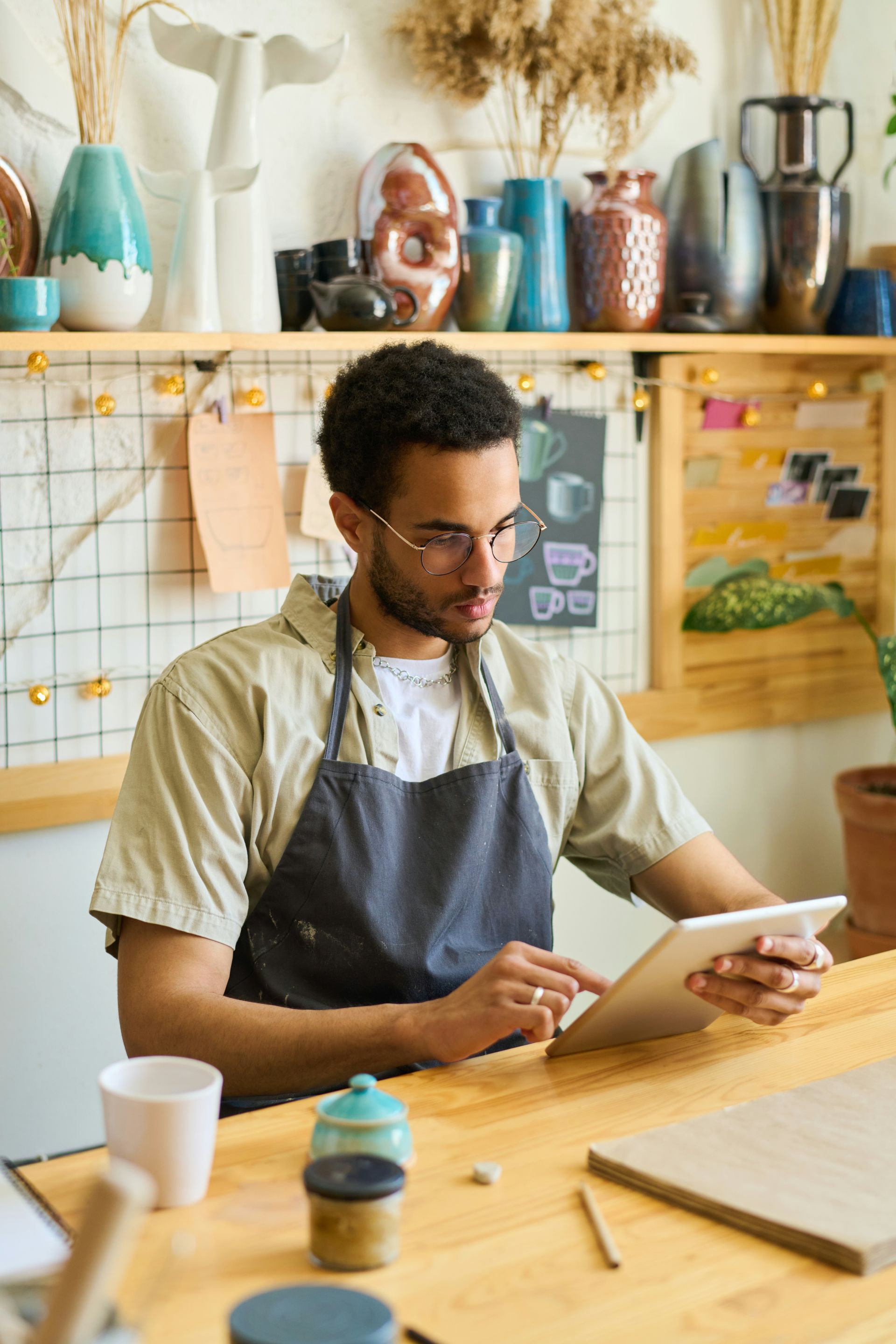 A man is sitting at a table using a tablet computer.