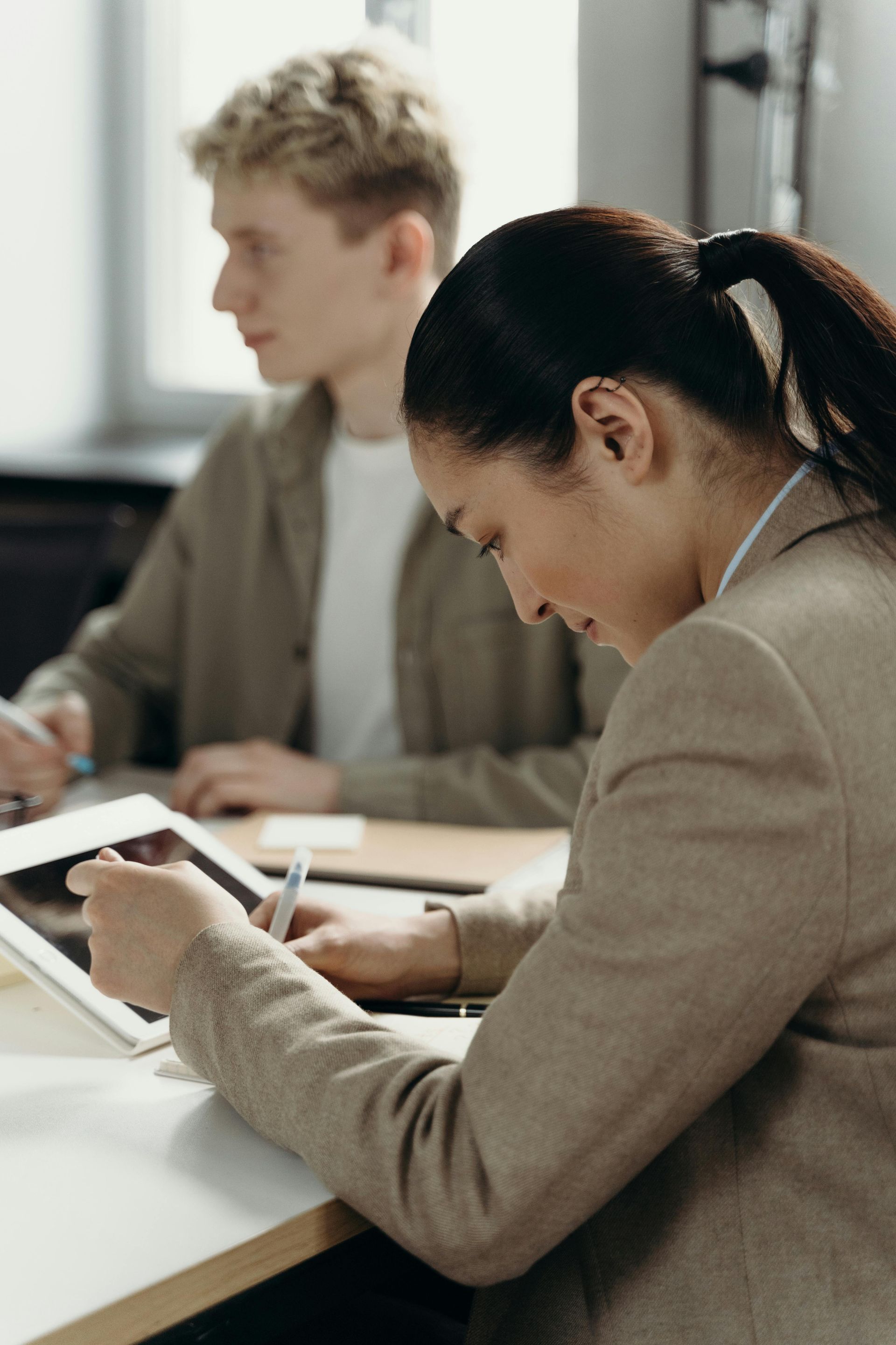A man and a woman are sitting at a table using a tablet.