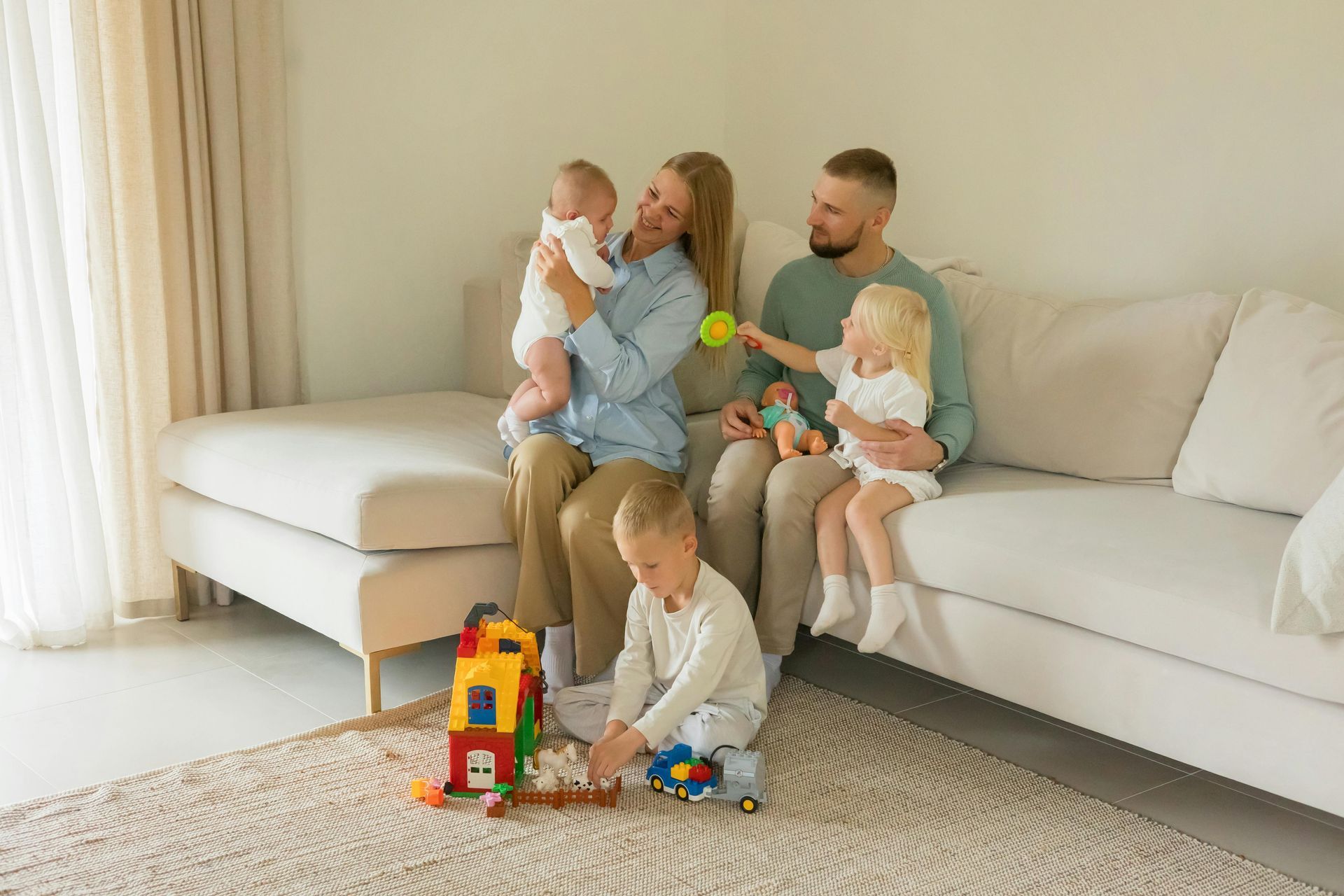 A family is sitting on a couch in a living room playing with toys.