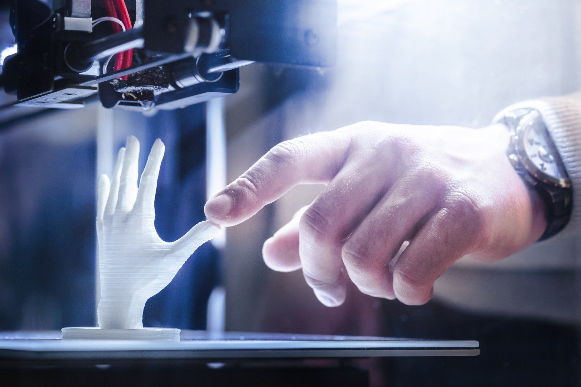 Una mano robotica si protende verso un dito umano in un laboratorio futuristico illuminato di blu.