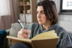 Woman on Sofa Writing on Her Journal – Anchorage, AK – Counseling Solutions of Alaksa LLC Woman on Sofa Writing on Her Journal – Anchorage, AK – Counseling Solutions of Alaksa LLC